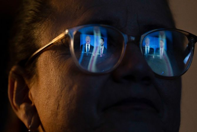 The debate is reflected in a woman's glasses as she watches from the Arizona GOP headquarters in Phoenix.