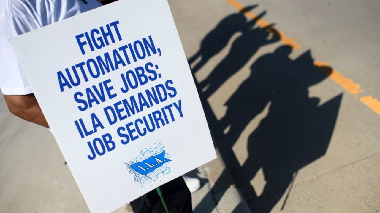 A striking worker holds up a sign in front of the Bayport Container Terminal in Seabrook, Texas, on October 3, 2024. The International Longshoremen's Association (ILA), 85,000 members strong, has launched its first strike since 1977 after weeks of deadlocked negotiations over a six-year labor agreement. (Photo by Mark Felix / AFP) (Photo by MARK FELIX/AFP /AFP via Getty Images)