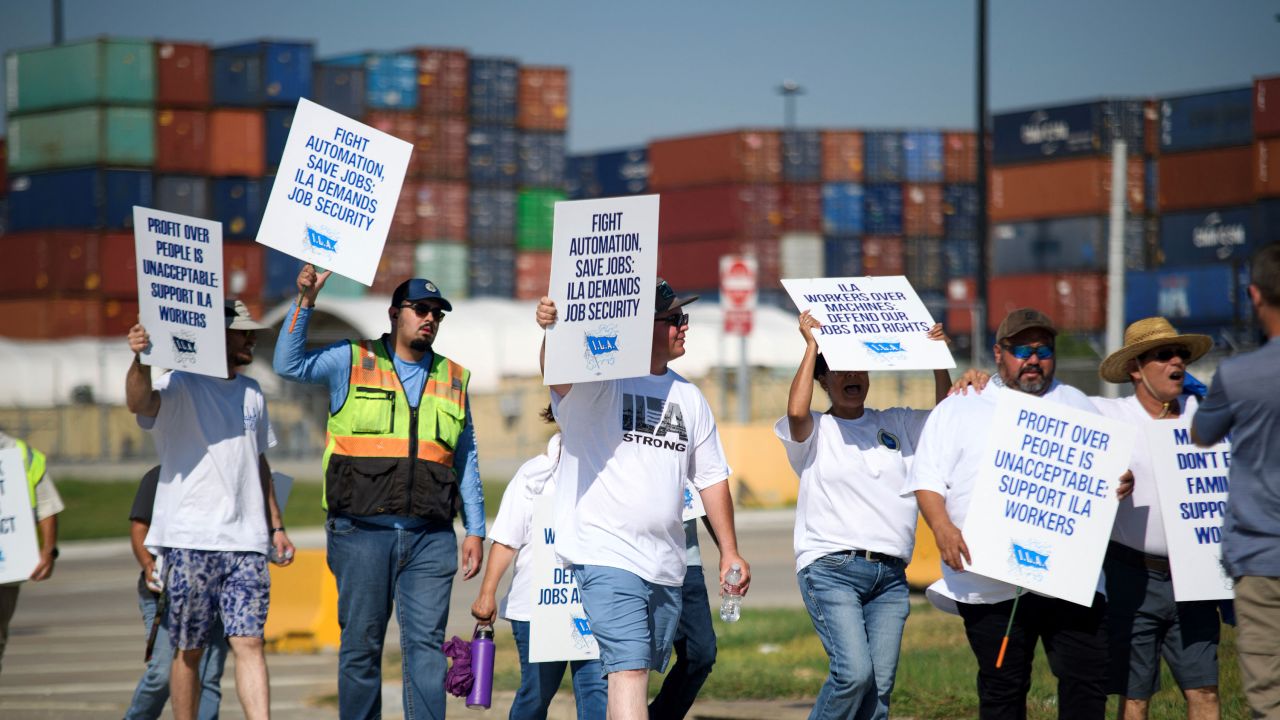 Striking workers hold up signs and march in front of the Bayport Container Terminal in Seabrook, Texas, on October 3, 2024. The International Longshoremen's Association (ILA), 85,000 members strong, has launched its first strike since 1977 after weeks of deadlocked negotiations over a six-year labor agreement.