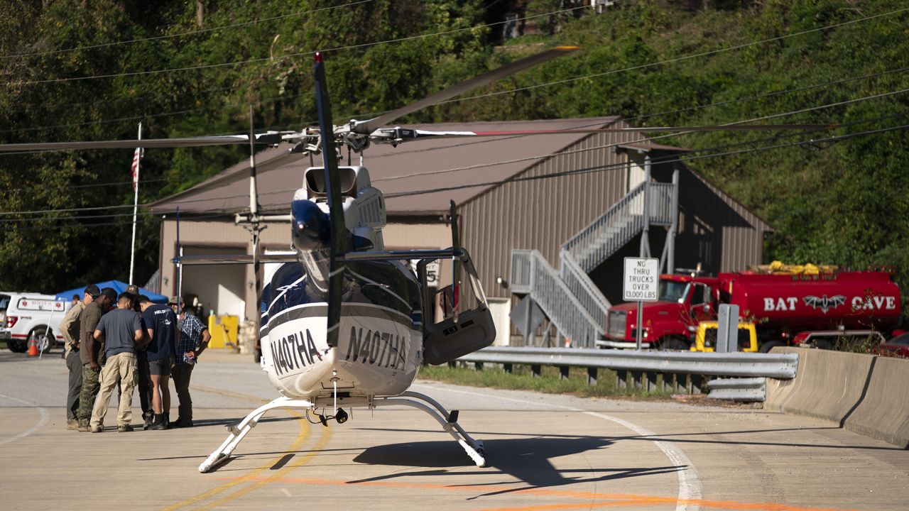 A helicopter pilot meets with people on the ground in the aftermath of Hurricane Helene on October 3, 2024, in Bat Cave, North Carolina.