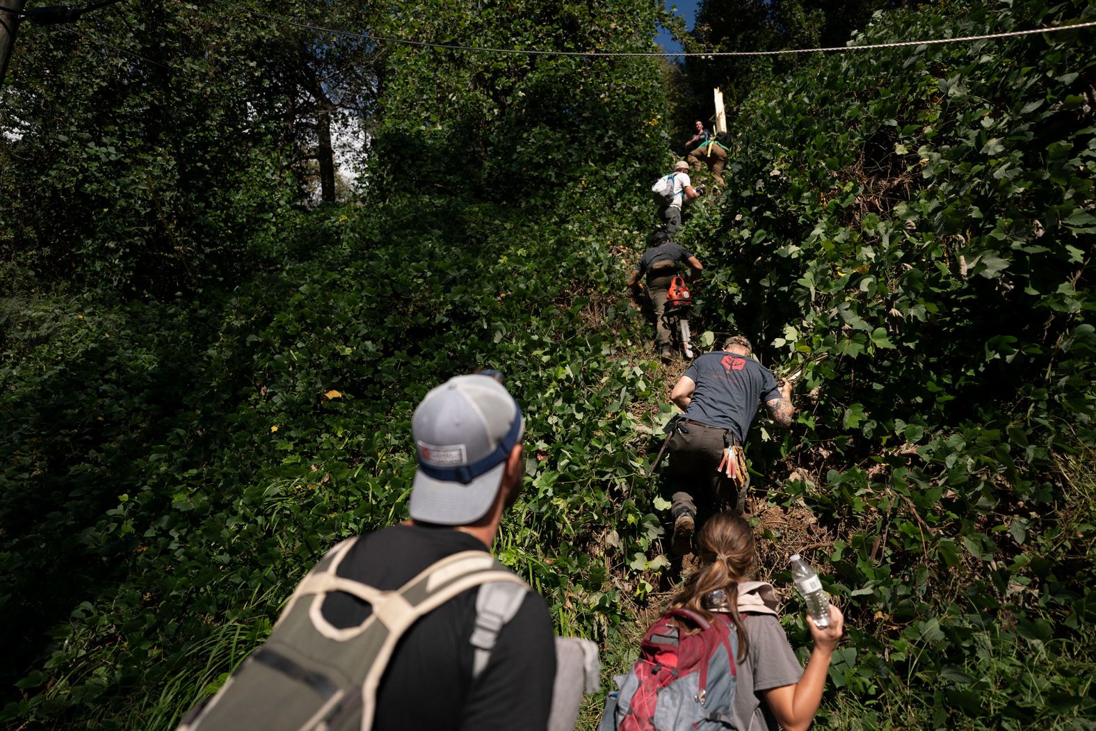 A relief group climbs up the side of a hill as they help near Bat Cave, North Carolina, on Thursday. The group was tasked with clearing roads and checking on people isolated because of Helene.