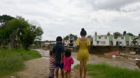 Children look at houses that collapsed due to the current of the stream that rose with the heavy rains following Hurricane John in Acapulco, Guerrero State, Mexico, on October 3, 2024. John made landfall last week as a Category 3 hurricane before churning along the coast for several days and striking land again as a tropical storm. (Photo by Francisco ROBLES / AFP) (Photo by FRANCISCO ROBLES/AFP via Getty Images)