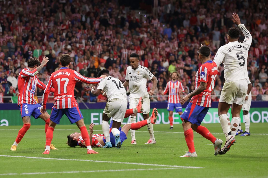 Atlético Madrid's Robin Le Normand falls to the ground after unintended clash of heads with Aurélien Tchouaméni