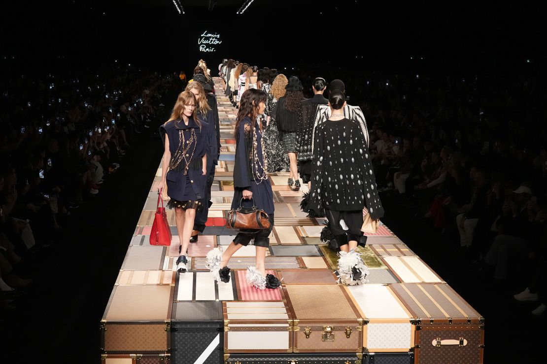 Models walk a runway created from the brand's iconic trunks at Louis Vuitton. 