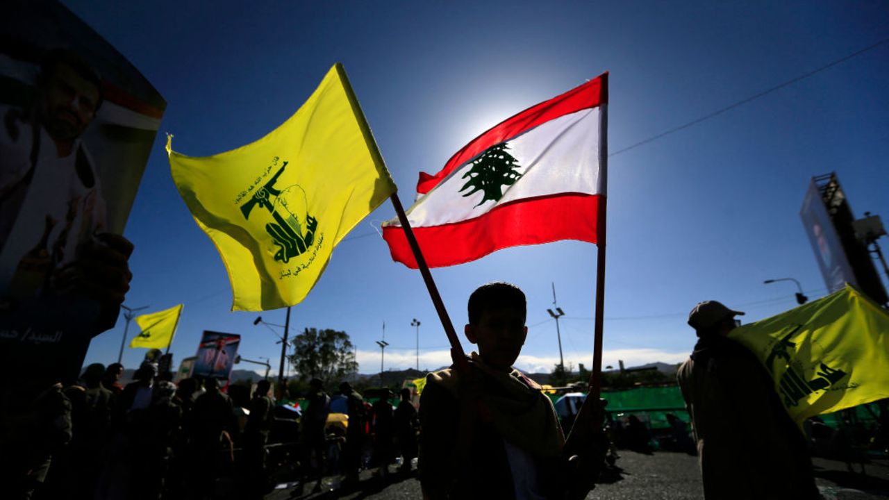 A Yemeni raises a Lebanese Hezbollah (L) and a national flag during a rally held in the Huthi-controlled capital Sanaa on October 4, 2024, in protest against Israel's attacks on Lebanon and the ongoing war between Israel and Hamas militants in the Gaza Strip. The US military said on October 4 that it struck 15 targets in areas of Yemen controlled by Huthi rebels, who have fired missiles at Israel and repeatedly attacked global shipping in the Red Sea. (Photo by Mohammed HUWAIS / AFP) (Photo by MOHAMMED HUWAIS/AFP via Getty Images)