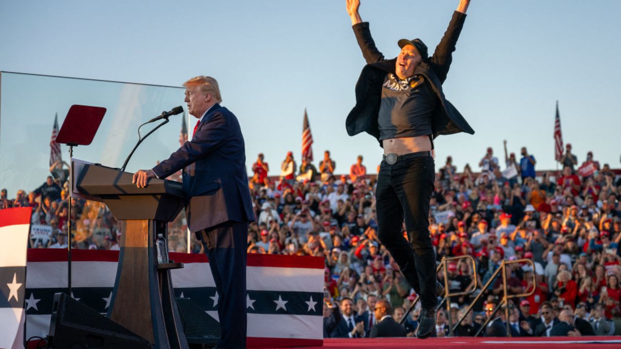 TOPSHOT - Tesla CEO Elon Musk (R) jumps on stage as he joins former US President and Republican presidential candidate Donald Trump during a campaign rally at site of his first assassination attempt in Butler, Pennsylvania on October 5, 2024. (Photo by Jim WATSON / AFP) (Photo by JIM WATSON/AFP via Getty Images)