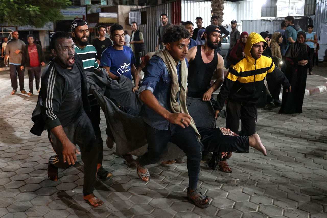 Palestinians carry one of the victims of an Israeli strike that targeted a mosque-turned-shelter in Deir al-Balah in the central Gaza Strip, in the courtyard of the al-Aqsa Martyrs hospital during the night of October 6.