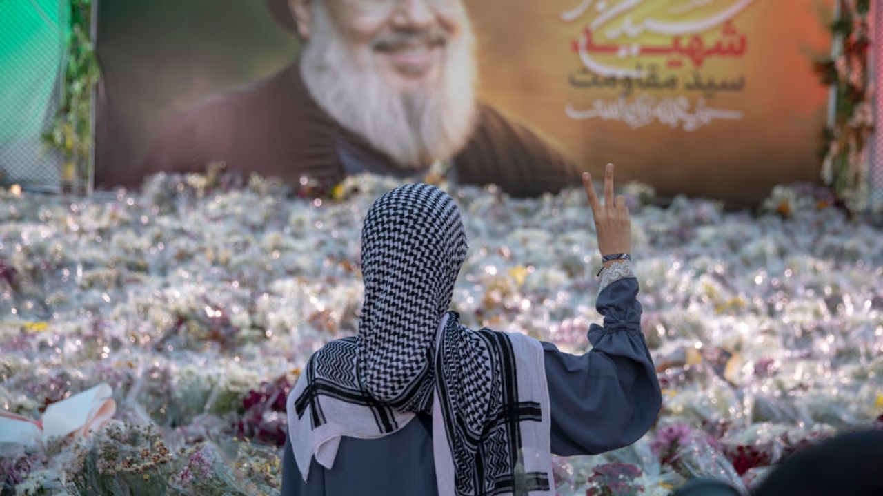 TEHRAN, IRAN - OCTOBER 2: An Iranian woman paying her respects and laying flowers in front of Hassan Nasrallah's banner in Palestine Square, on October 2, 2024 in Tehran, Iran. Hassan Nasrallah was a Lebanese politician and cleric who served as the secretary-general of Hezbollah for 32 years. He was killed in the southern suburbs of Beirut by an Israeli airstrike. (Photo by Majid Saeedi/Getty Images)