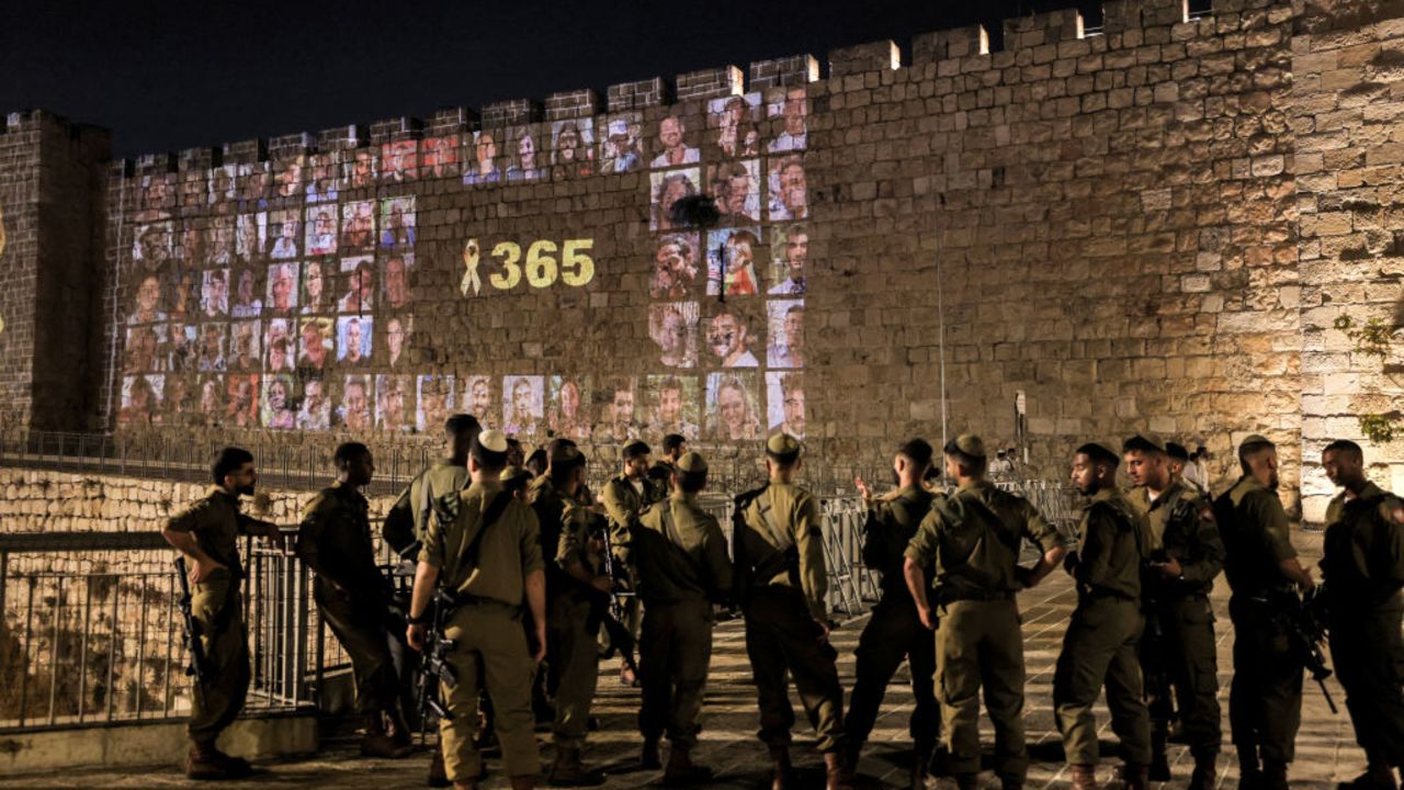 Israeli army soldiers stand by as a yellow ribbon along with the number 365, signifying the number of days since the October 7, 2023 attacks carried out by Palestinian militants from the Gaza Strip, is projected along with pictures of the victims of the attacks along the old city walls of Jerusalem late on October 6, 2024 on the eve of the first anniversary of the war that began with the attacks. (Photo by AHMAD GHARABLI / AFP) (Photo by AHMAD GHARABLI/AFP via Getty Images)