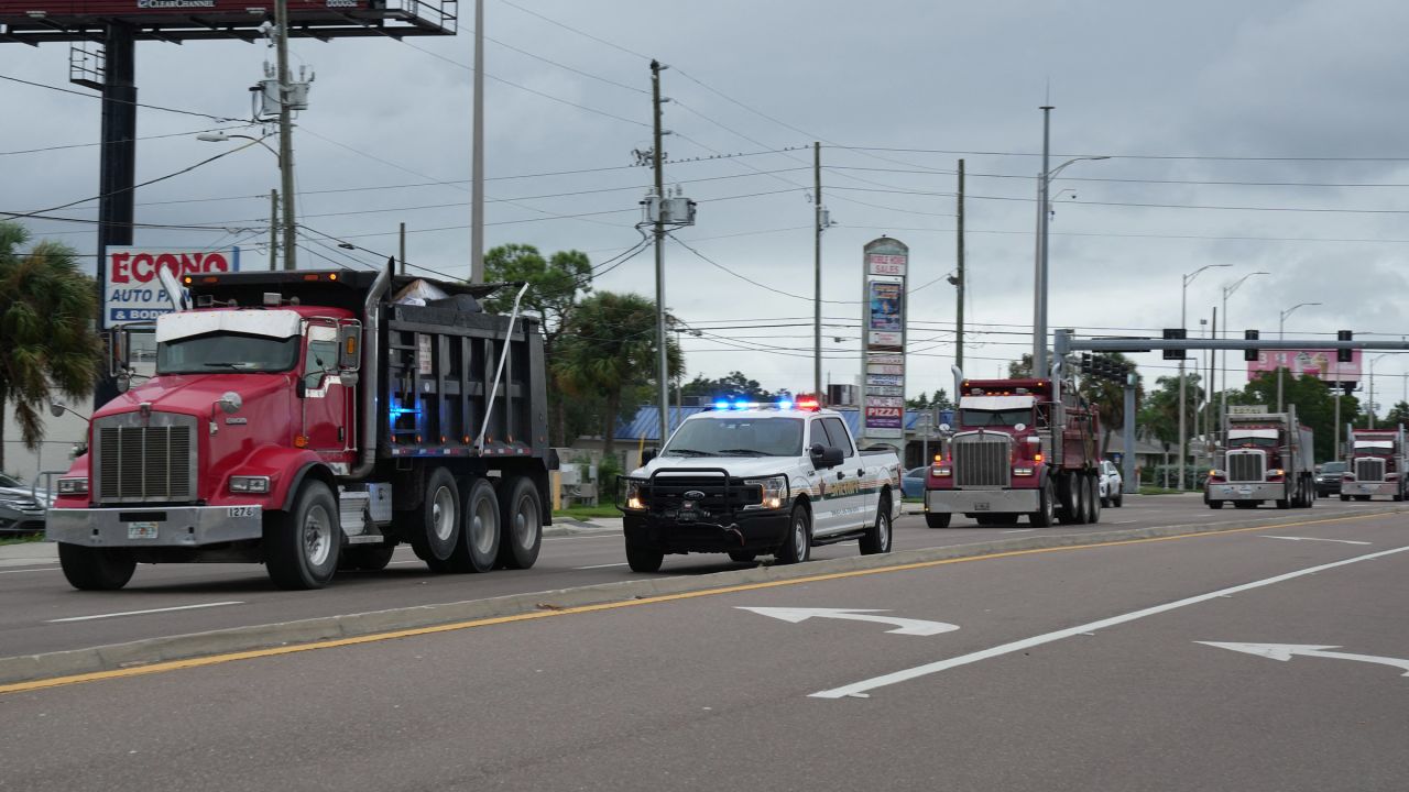 Pinellas County sheriff's deputies escort dump trucks filled with debris from Hurricane Helene to a landfill in Clearwater, Florida, on October 6, 2024, ahead of Hurricane Milton's landfall.