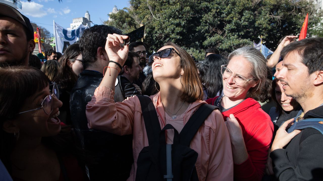 BUENOS AIRES, ARGENTINA - OCTOBER 02: A woman watches the solar annular eclipse during the second nationwide demonstration against president Milei's budget-cuts to public universities on October 02, 2024 in Buenos Aires, Argentina. The march have been called by university authorities and students after the President of Argentina Javier Milei warned that he will veto a law that improves the budget of high education institutions. (Photo by Tobias Skarlovnik/Getty Images)