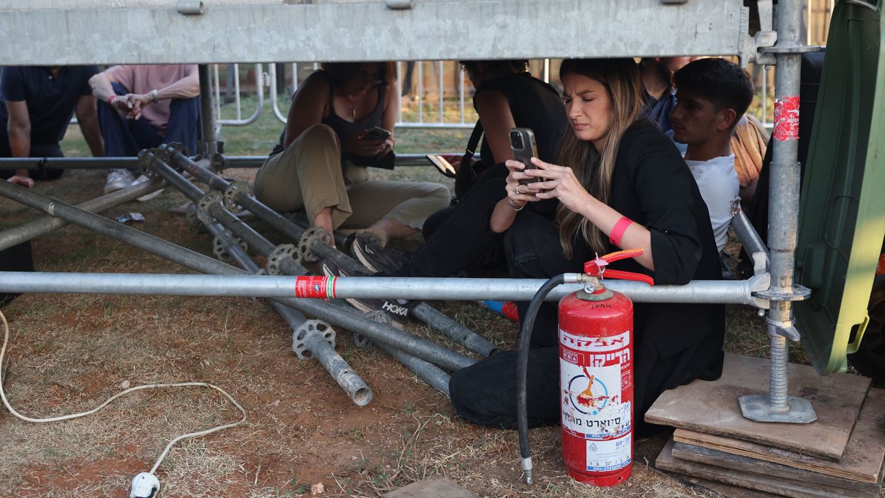 People take cover as sirens sound to warn of incoming rockets in the Israeli coastal city of Tel Aviv on October 7.