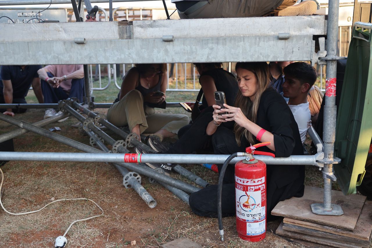 People take cover as sirens sound to warn of incoming rockets in the Israeli coastal city of Tel Aviv on October 7.