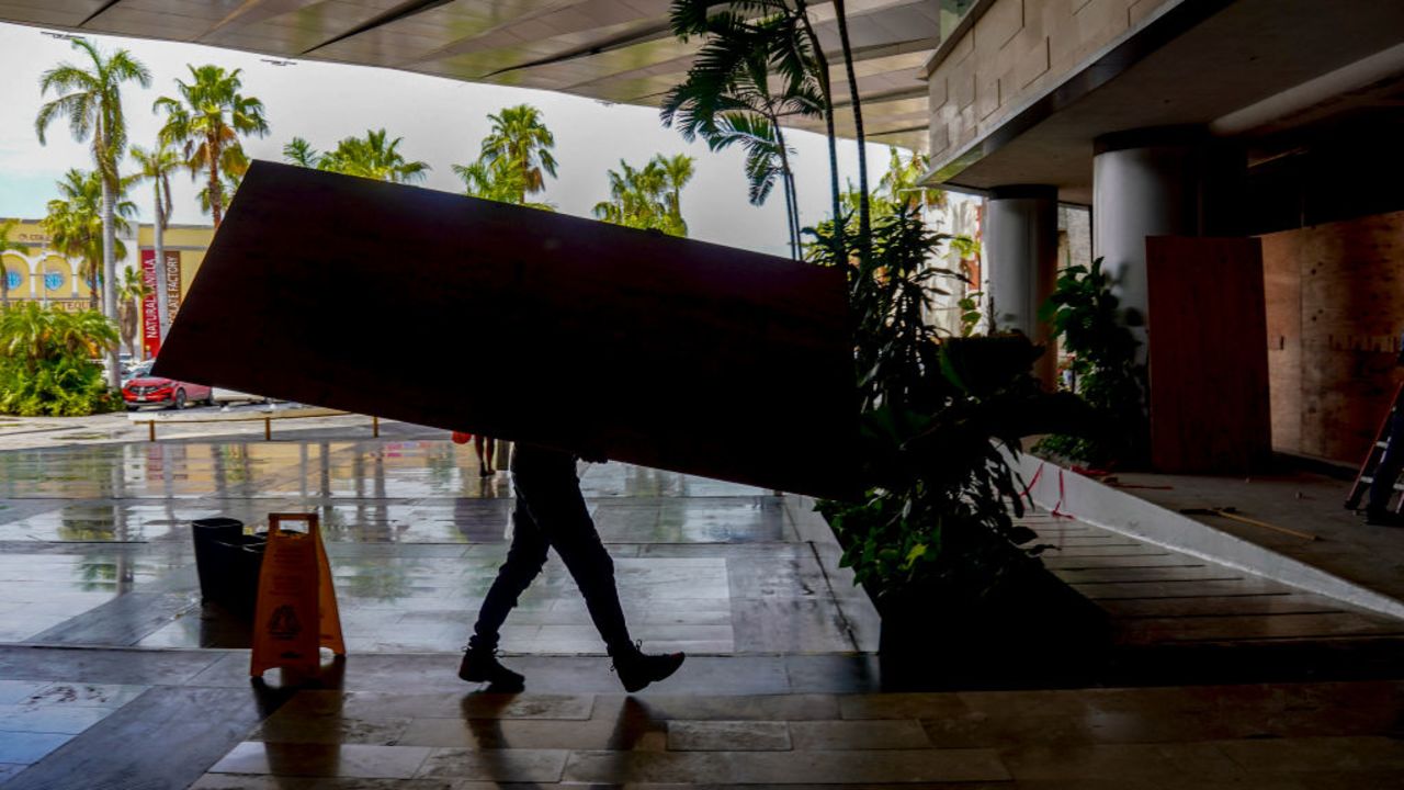 A worker places sheets of wood over windows and glass doors to protect them from the strong winds expected with the arrival of Hurricane Milton in the hotel zone of Cancun, Quintana Roo State, Mexico, on October 7, 2024. Hurricane Milton exploded in strength Monday to become a potentially catastrophic Category 5 storm bound for Florida, threatening the US state with a second ferocious storm in as many weeks. Milton, which is also forecast to graze Mexico's Yucatan peninsula as it churns eastward, rapidly intensified to the highest category on a scale of five, triggering evacuation orders and alarms about a life-threatening storm surge in major population centers, including Tampa Bay. (Photo by Elizabeth RUIZ / AFP) (Photo by ELIZABETH RUIZ/AFP via Getty Images)