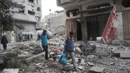 People carry salvaged items amid the rubble of buildings damaged during an Israeli air strike the previous night on the Bureij refugee camp in the central Gaza Strip on October 8, 2024, amid the continuing war between Israel and the Palestinian militant group Hamas. (Photo by Eyad BABA / AFP) (Photo by EYAD BABA/AFP via Getty Images)