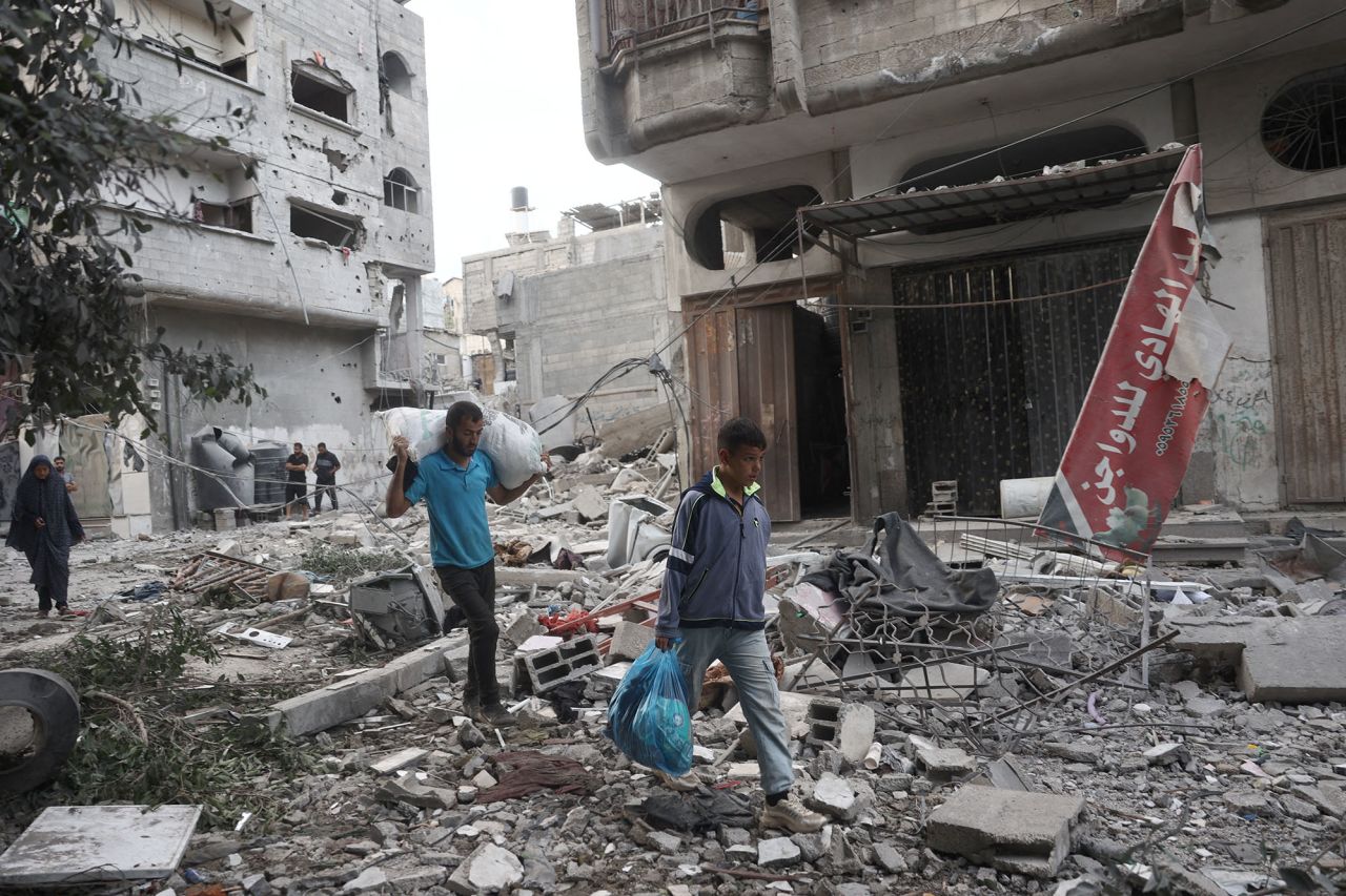 People carry salvaged items amid the rubble of buildings damaged during an Israeli air strike the previous night at the Bureij refugee camp, Gaza, on October 8.