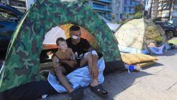 TOPSHOT - A wounded displaced man sits with his child inside their tent in central Beirut's Ain al-Mreisseh seaside promenade on October 7, 2024. Intense Israeli attacks may have forced up to a million people to flee parts of Lebanon in possibly the worst displacement crisis in the tiny country's history, Lebanon's Prime Minister Najib Mikati said on September 29. (Photo by AFP) (Photo by -/AFP via Getty Images)