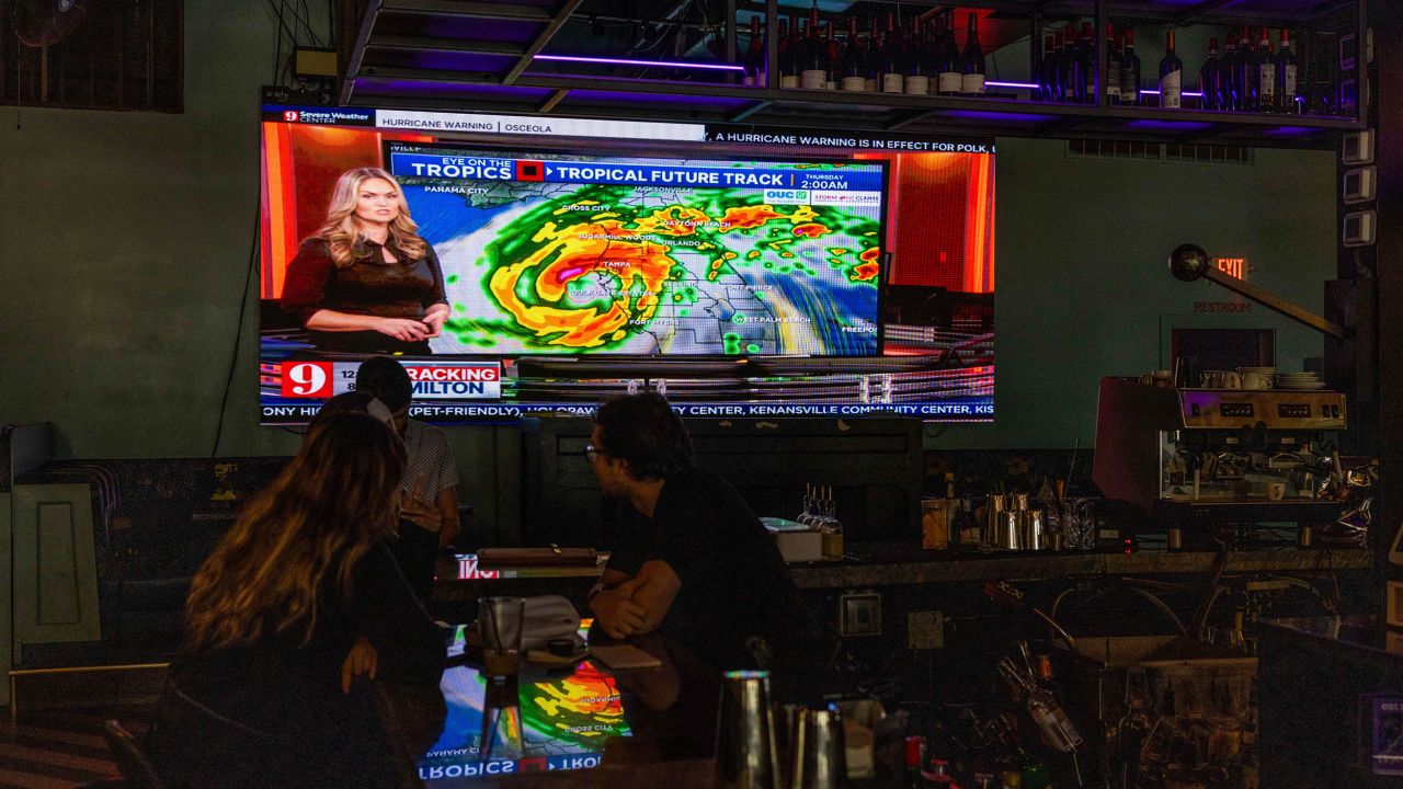 ORLANDO, FLORIDA - OCTOBER 8: People watch a television screen at a bar showing the local news channel as the community prepares for Hurricane Milton on October 8, 2024 in Orlando, Florida. Milton, which came just after the recent catastrophic hurricane Helene, has strengthened to a Category 5 storm as it approaches Florida's central Gulf Coast and is expected to make landfall midweek. (Photo by Saul Martinez/Getty Images)