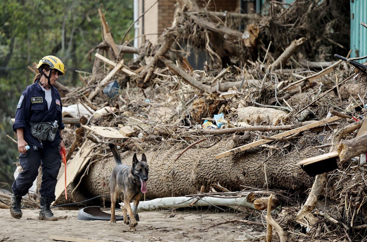 A member of the FEMA Urban Search and Rescue Task Force searches a flood-damaged property with a search canine in the aftermath of Hurricane Helene along the Swannanoa River on October 4 in Asheville, North Carolina.