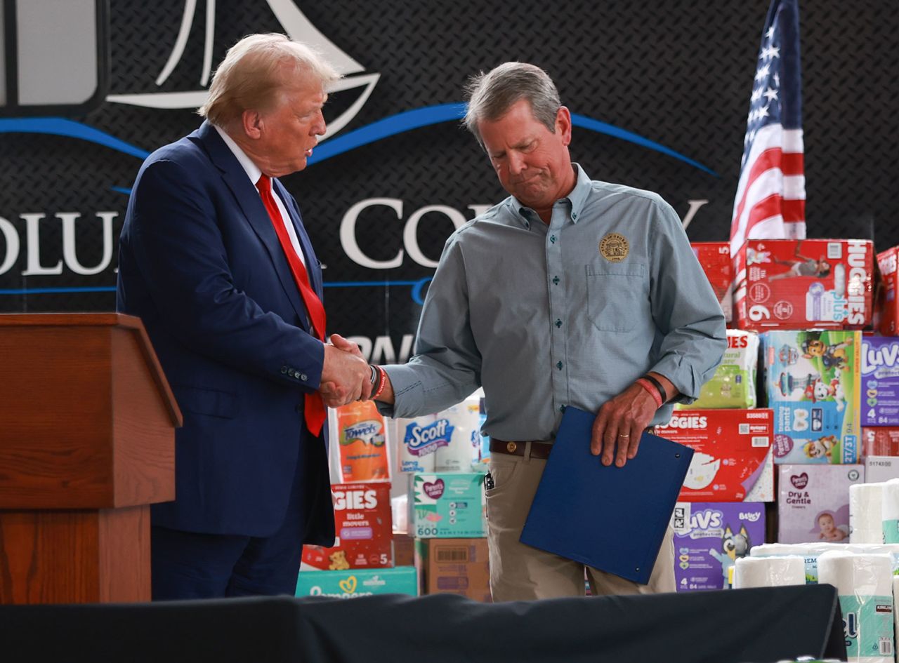 Former President Donald Trump shakes hands with Georgia Gov. Brian Kemp as they visit the area while the people recover from Hurricane Helene on October 4 in Evans, Georgia.