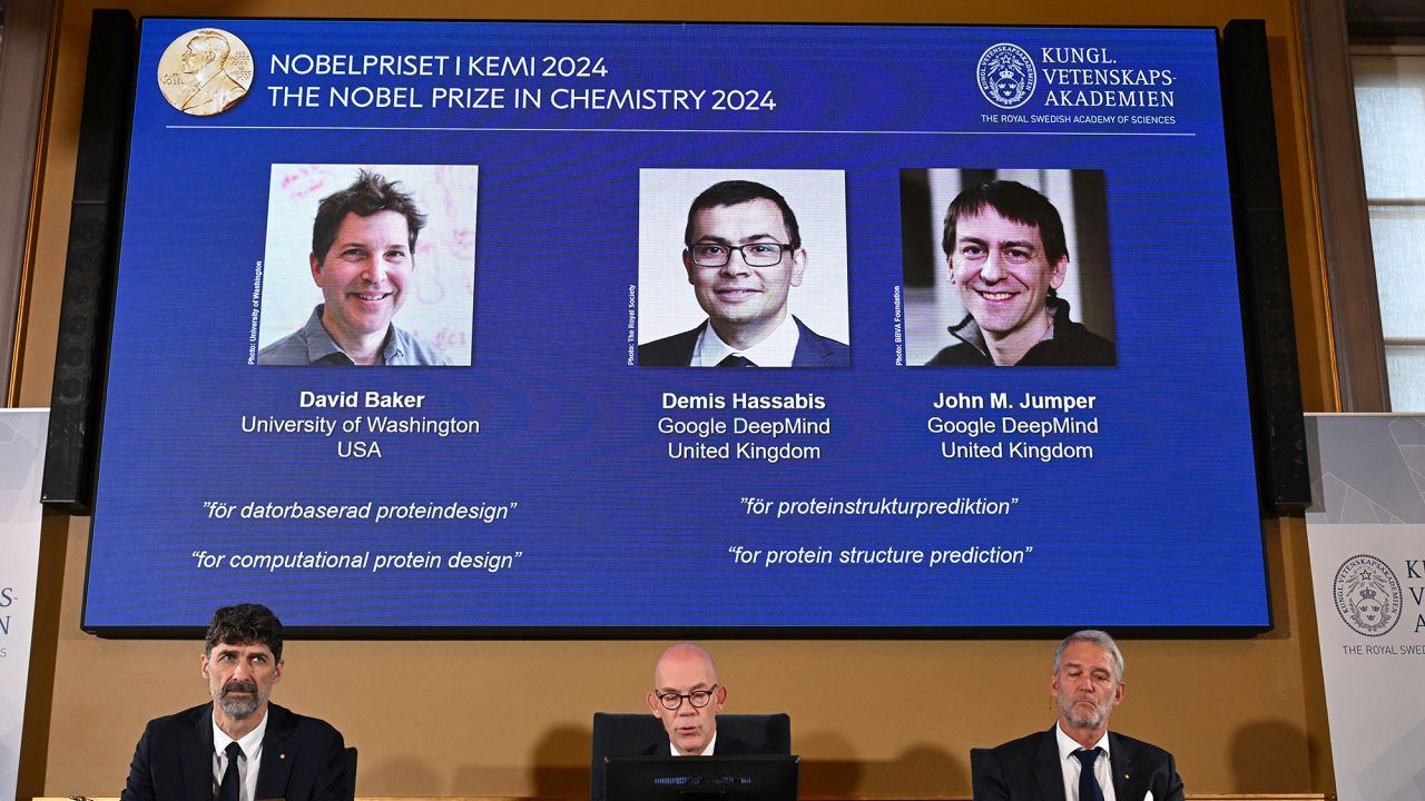 (L-R) Heiner Linke, chair of the Nobel Committee for Chemistry at the Royal Swedish Academy of Sciences, the Secretary General of the Royal Swedish Academy of Sciences Hans Ellegren and member of the Nobel Committee for Chemistry Johan Aqvist sit in front of a screen depicting the laureates (L-R) David Baker, Demis Hassabis and John M. Jumper of the 2024 Nobel Prize in Chemistry during the announcement by the Royal Swedish Academy of Sciences in Stockholm, Sweden on October 9, 2024. (Photo by Jonathan NACKSTRAND / AFP) (Photo by JONATHAN NACKSTRAND/AFP via Getty Images)