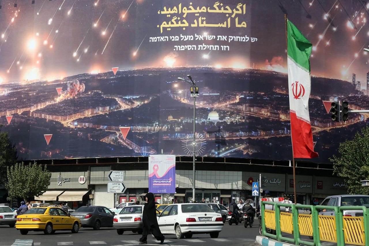 People walk on the streets of Tehran, Iran, where Iranian flags and Hezbollah banners are seen, on October 9.