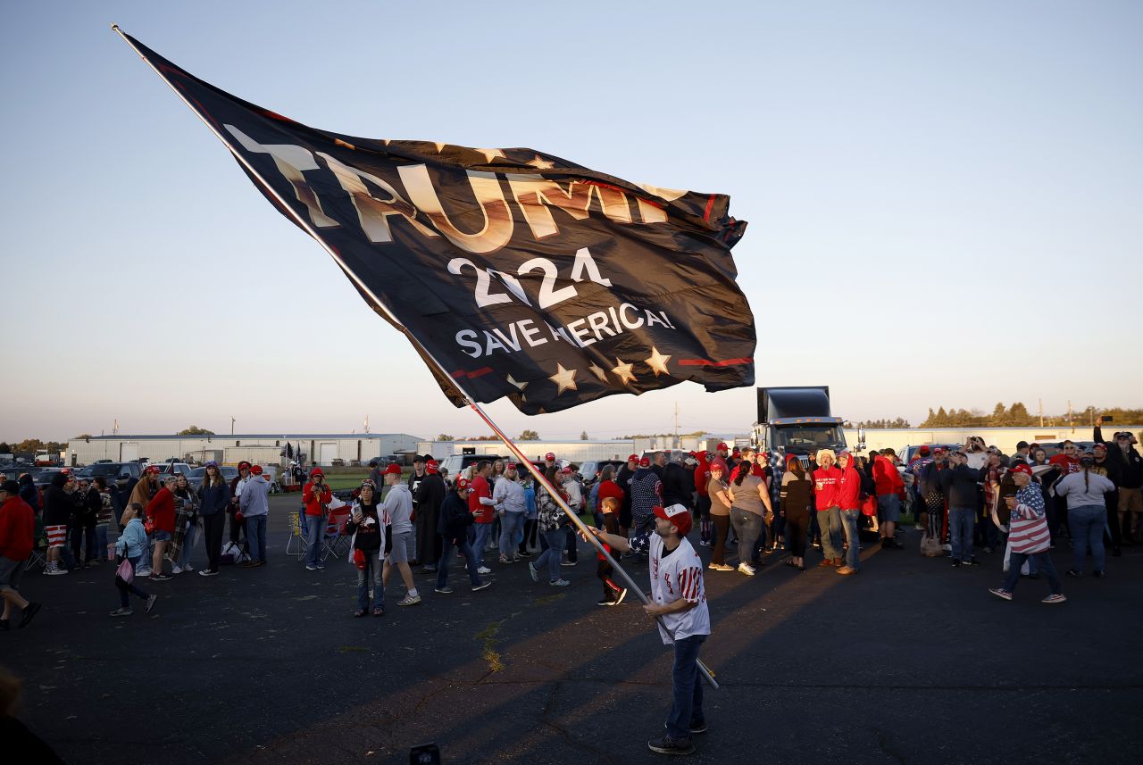 BUTLER, PENNSYLVANIA - OCTOBER 05: A man waves a flag as attendees wait in line prior to a rally by Republican presidential nominee, former U.S. President Donald Trump, at the Butler Farm Show Inc. on October 05, 2024 in Butler, Pennsylvania. Trump is holding a rally in Butler at the site of his first assassination attempt. (Photo by Kevin Dietsch/Getty Images)