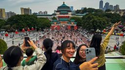 A group of young women take selfies in front of Chongqing's People’s Great Hall during the National Day Golden Week holiday on October 5, 2024, in Chongqing, China.