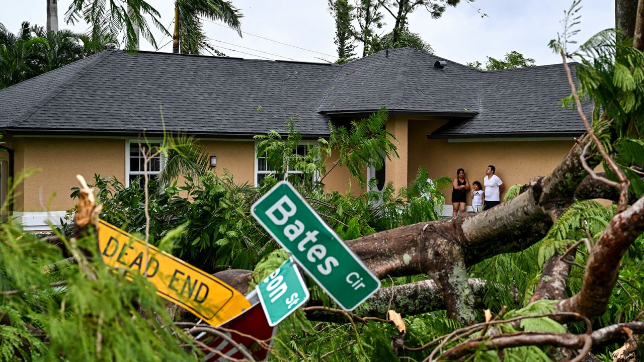 Oscar Garcia and his family stand outside his house after it was hit by a reported tornado in Fort Myers, Florida, during the approach of Hurricane Milton on October 9, 2024.