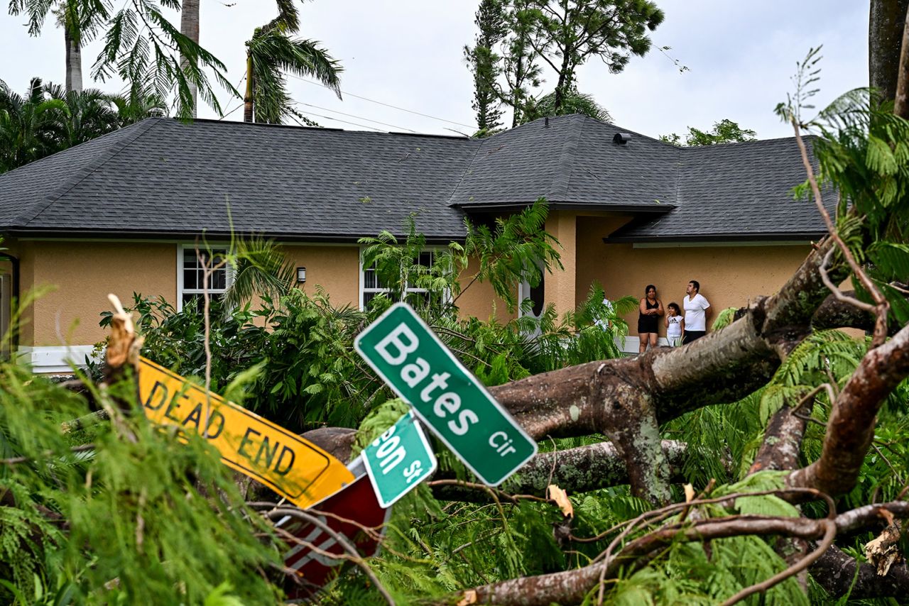 Oscar Garcia and his family stand outside his house after it was hit by a reported tornado in Fort Myers, Florida, during the approach of Hurricane Milton on October 9, 2024.