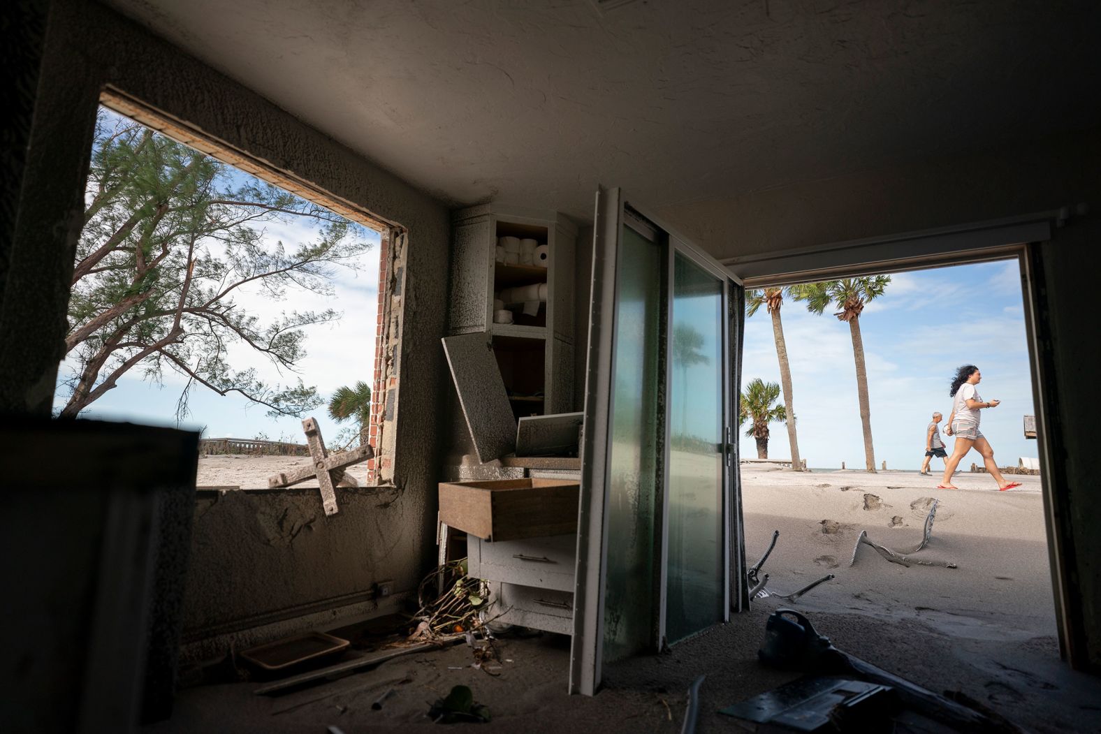 People walk near damaged beachside property in Venice on Thursday.