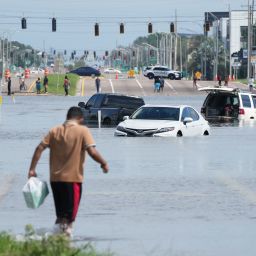 A young man walks past vehicles flooded in the water as the streets of the Southeast Seminole Heights section of Tampa due to Hurricane Milton on October 10, 2024 in Florida. Hurricane Milton tore a coast-to-coast path of destruction across the US state of Florida, whipping up a spate of deadly tornadoes that left at least four people dead, but avoiding the catastrophic devastation officials had feared. (Photo by Bryan R. SMITH / AFP) (Photo by BRYAN R. SMITH/AFP via Getty Images)