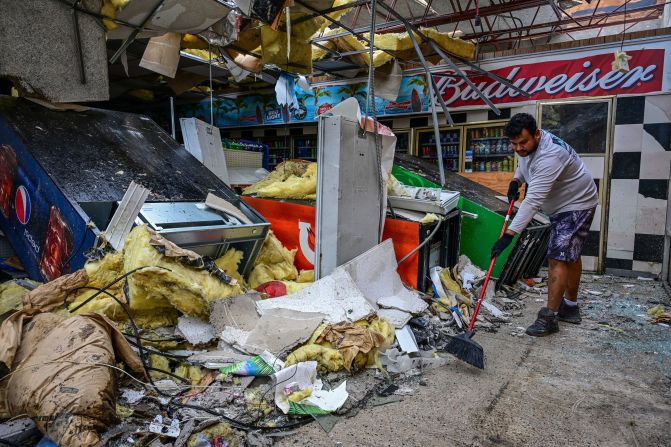 A man cleans debris inside a gas station in Lakewood Park, Florida, on Thursday, October 10. A tornado caused by Milton hit the area.