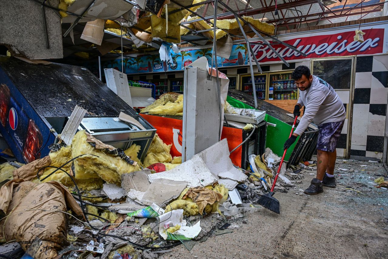 A man cleans debris inside a gas station store in Lakewood Park, Florida, after a tornado hit the area and caused severe damage as Hurricane Milton swept through Florida on October 10, 2024.