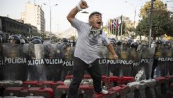 TOPSHOT - A member of the union of transporters and merchants shouts slogans in front of riot police during a protest against the wave of extortions in Lima on October 10, 2024. Dozens of transport workers and small traders held a protest march in Lima on Thursday, the second in less than two weeks against extortion and murder by organized crime. (Photo by Ernesto BENAVIDES / AFP) (Photo by ERNESTO BENAVIDES/AFP via Getty Images)