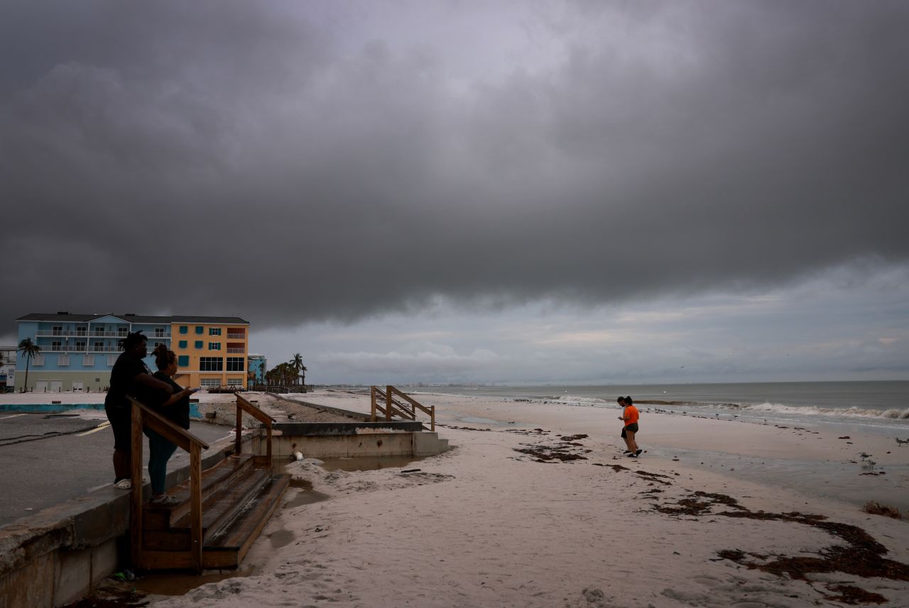 People visit the beach as storm clouds hang pass overhead before Hurricane Milton's arrival on October 8, in Fort Myers, Florida.