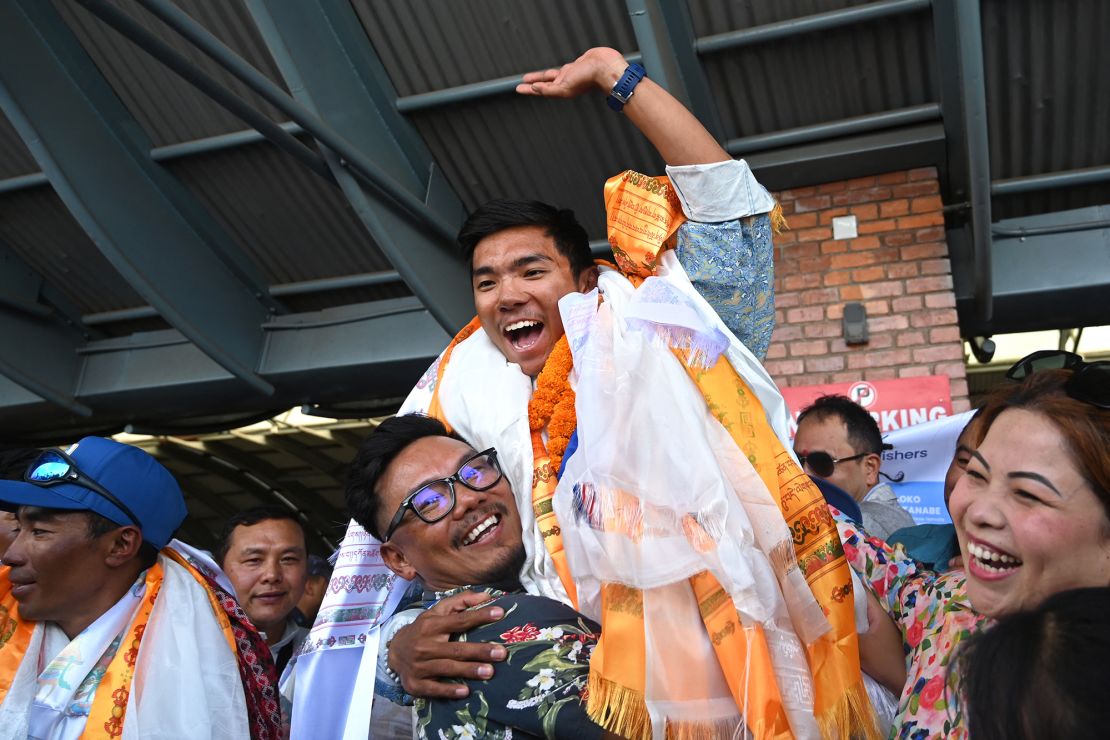 Nepali mountaineer Nima Rinji Sherpa waves upon his arrival at the airport in Kathmandu on October 14, 2024.