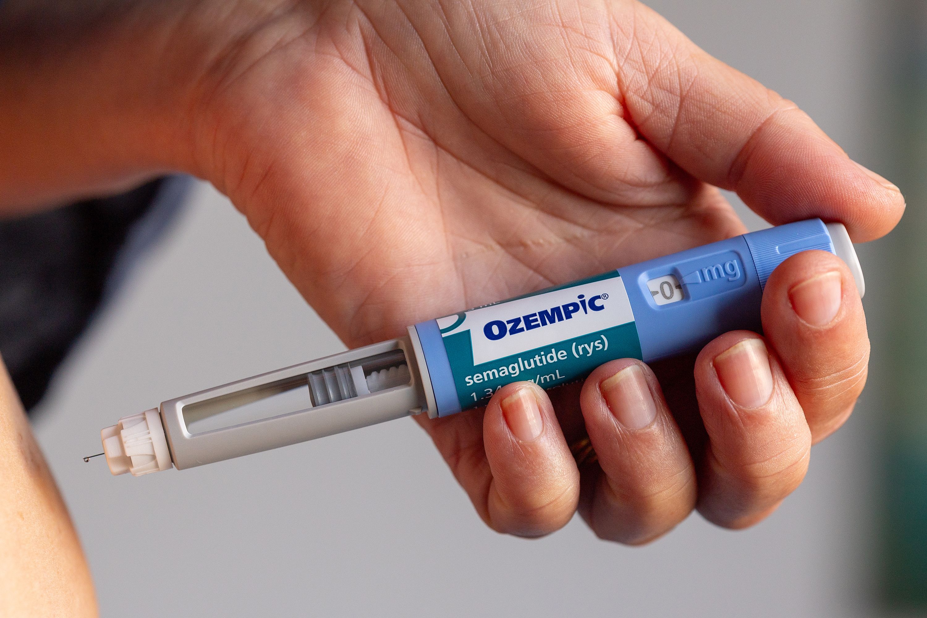 Hand holding an Ozempic pen (semaglutide) showing the device used for injections.