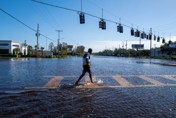 A person walks through a flooded street from the rising Anclote River in New Port Richey, Florida, on Friday.