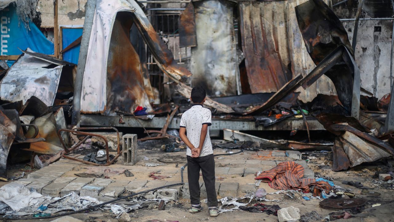 TOPSHOT - A Palestinian boy looks at destroyed shelters at the site of an Israeli airstrike which hit tents for displaced people two days earlier in the courtyard of Al-Aqsa Martyrs Hospital in Deir al-Balah in the central Gaza Strip on October 16, 2024. A spokesman for the Palestinian Civil Defence in Gaza said the October 14 strike had killed four people and wounded many more, noting it was the seventh time an attack had hit the "tents for displaced people inside the walls of Al-Aqsa Martyrs Hospital". (Photo by Eyad BABA / AFP) (Photo by EYAD BABA/AFP via Getty Images)