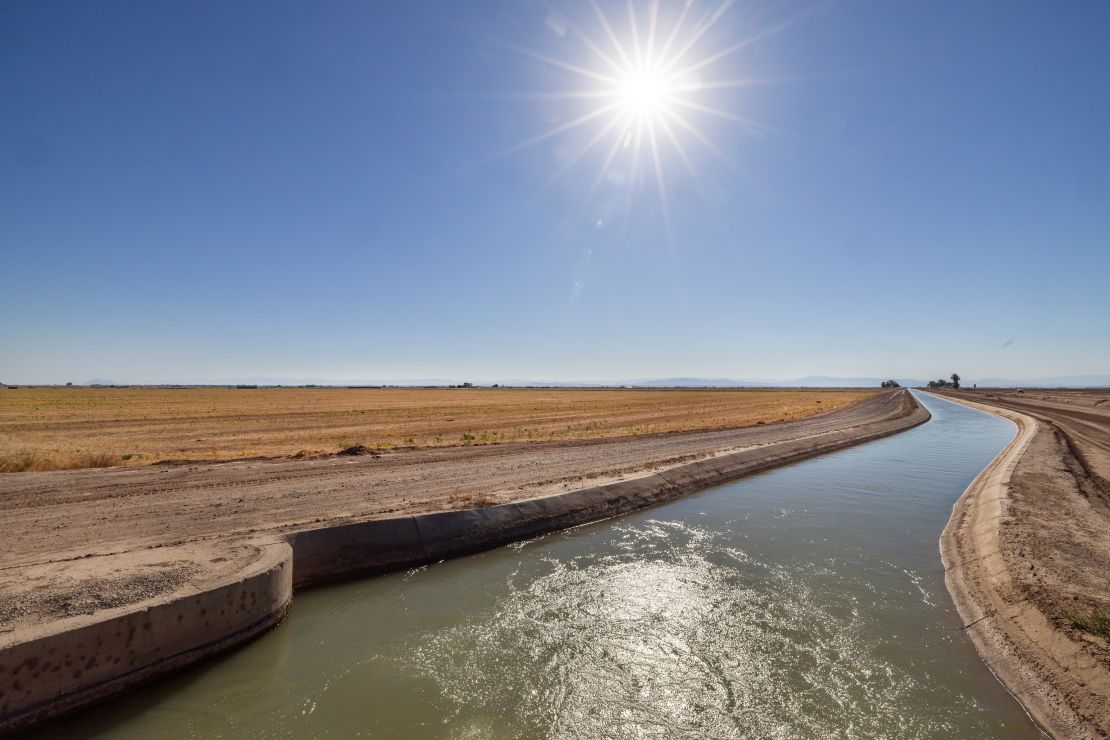 Colorado River water flowing through an aqueduct next to a dry alfalfa field in September.