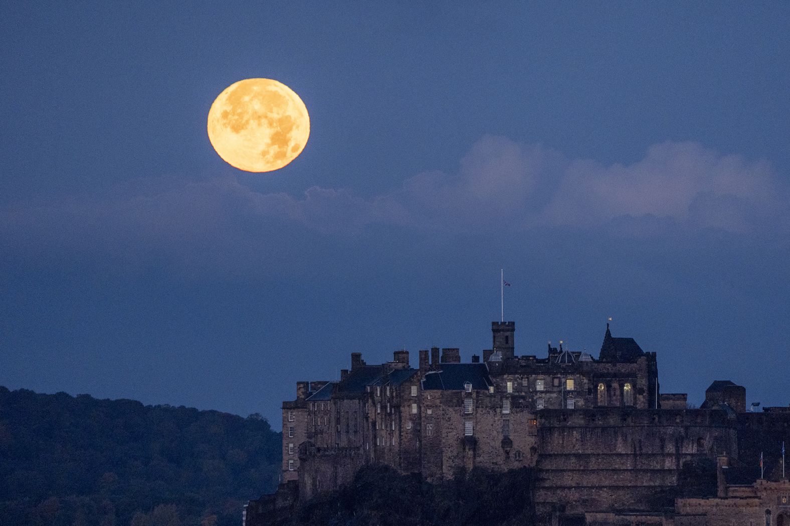 The moon sets behind Edinburgh Castle in Scotland on Thursday.