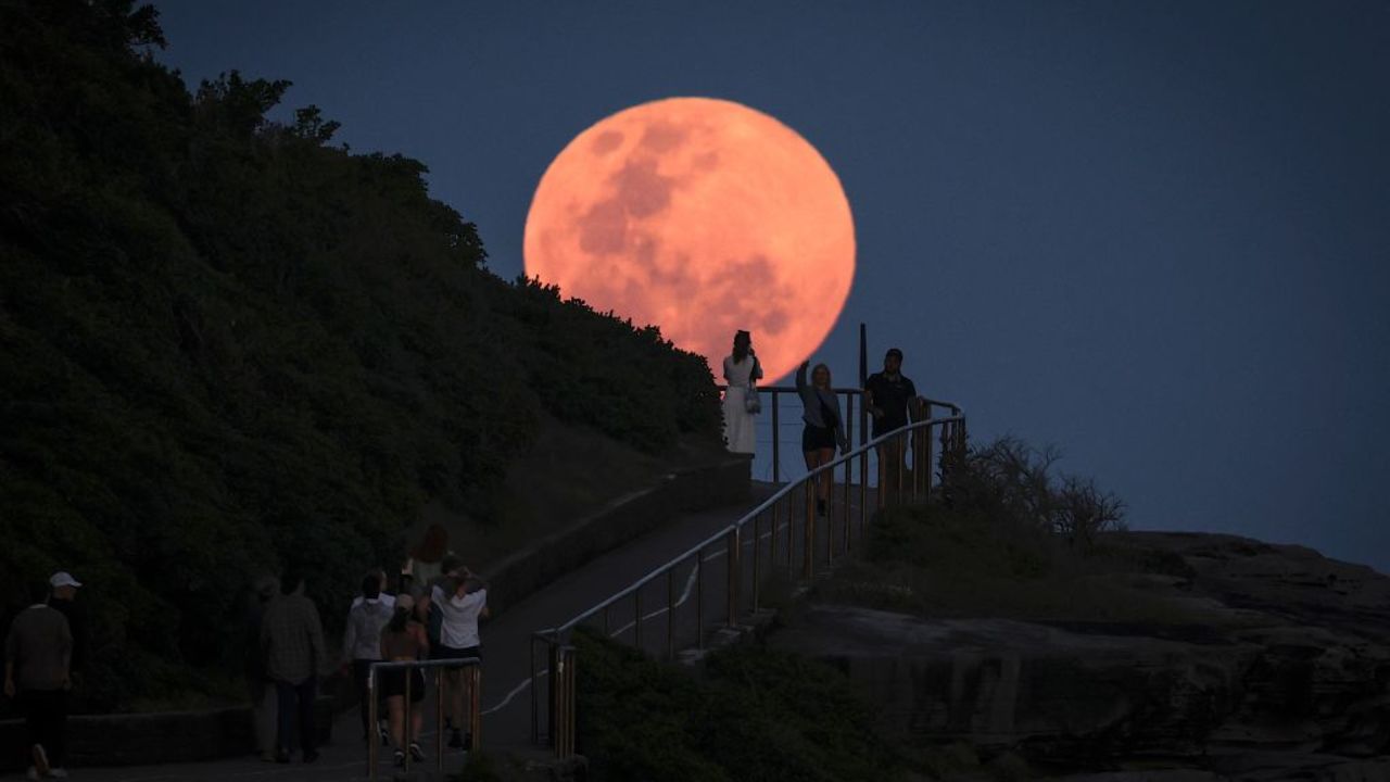 A super moon rises behind people standing on a headland near Sydney's Bondi Beach on October 17, 2024. (Photo by DAVID GRAY / AFP) (Photo by DAVID GRAY/AFP via Getty Images)