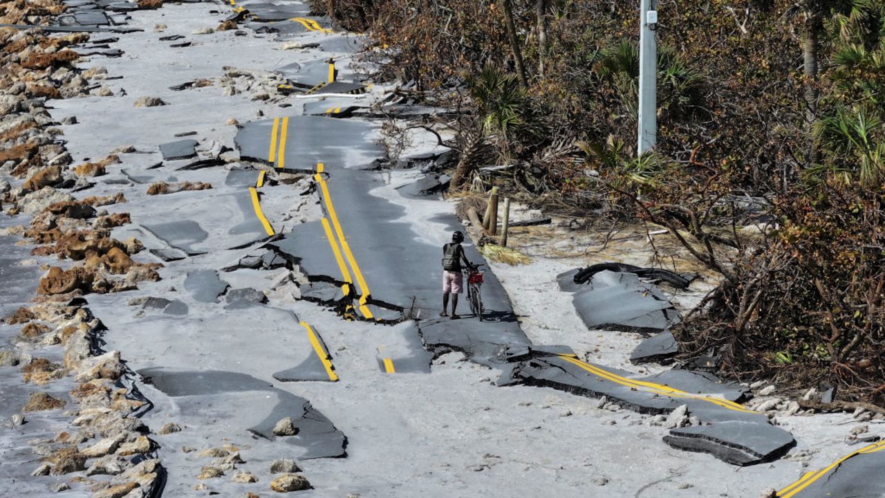 MANASOTA KEY, FLORIDA - OCTOBER 13: In an aerial view, a bicycle rider navigates a damaged road along the Gulf of Mexico on October 13, 2024 in Manasota Key, Florida. People continue recovering following the storm that made landfall as a Category 3 hurricane in the Siesta Key area of Florida on October 9th, causing damage and flooding throughout Central Florida. (Photo by Joe Raedle/Getty Images)