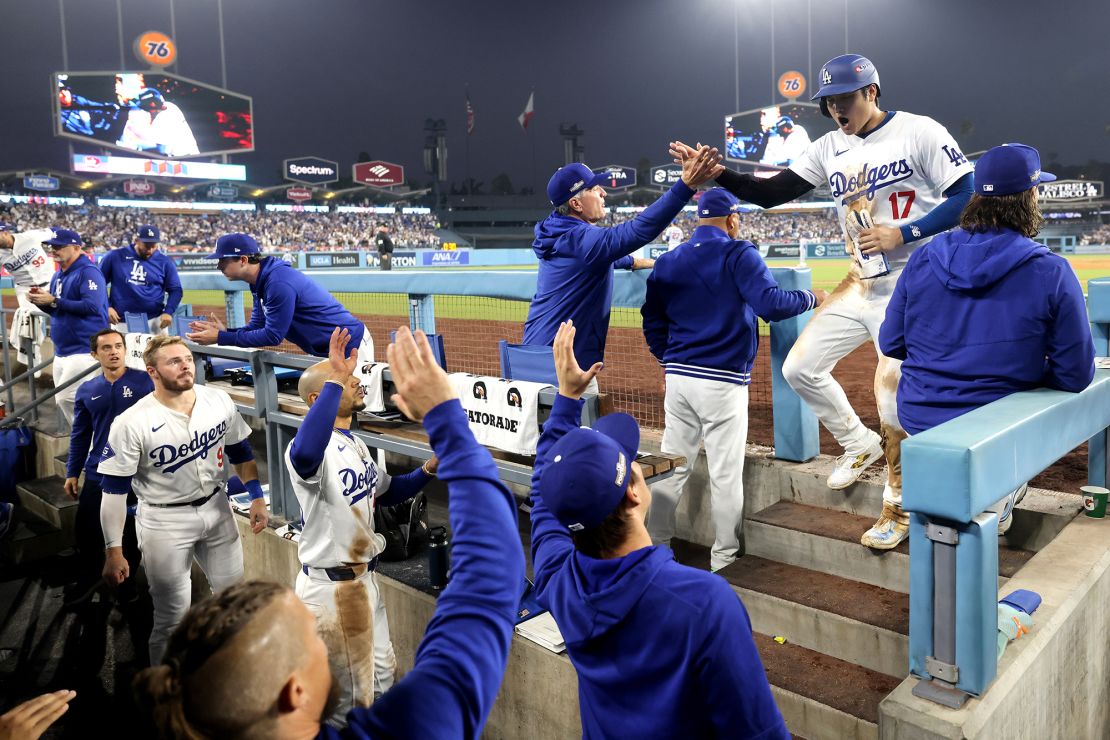 Two-time AL MVP Shohei Ohtani celebrating with teammates after scoring a run during Game 1 of the NLCS against the Mets at Dodger Stadium.