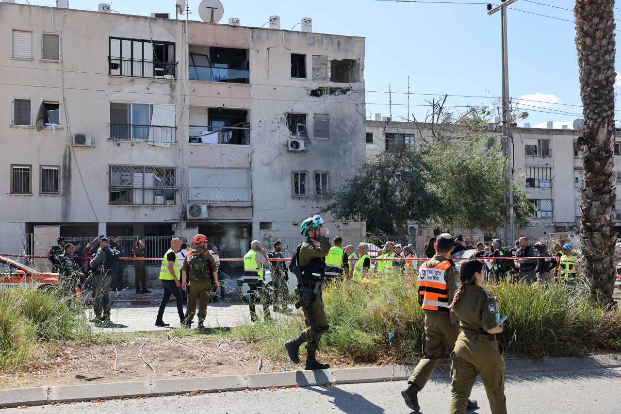 Israeli security forces gather in front of a building in Kiryat Ata, Israel, that was damaged by a rocket fired from Lebanon on October 19.