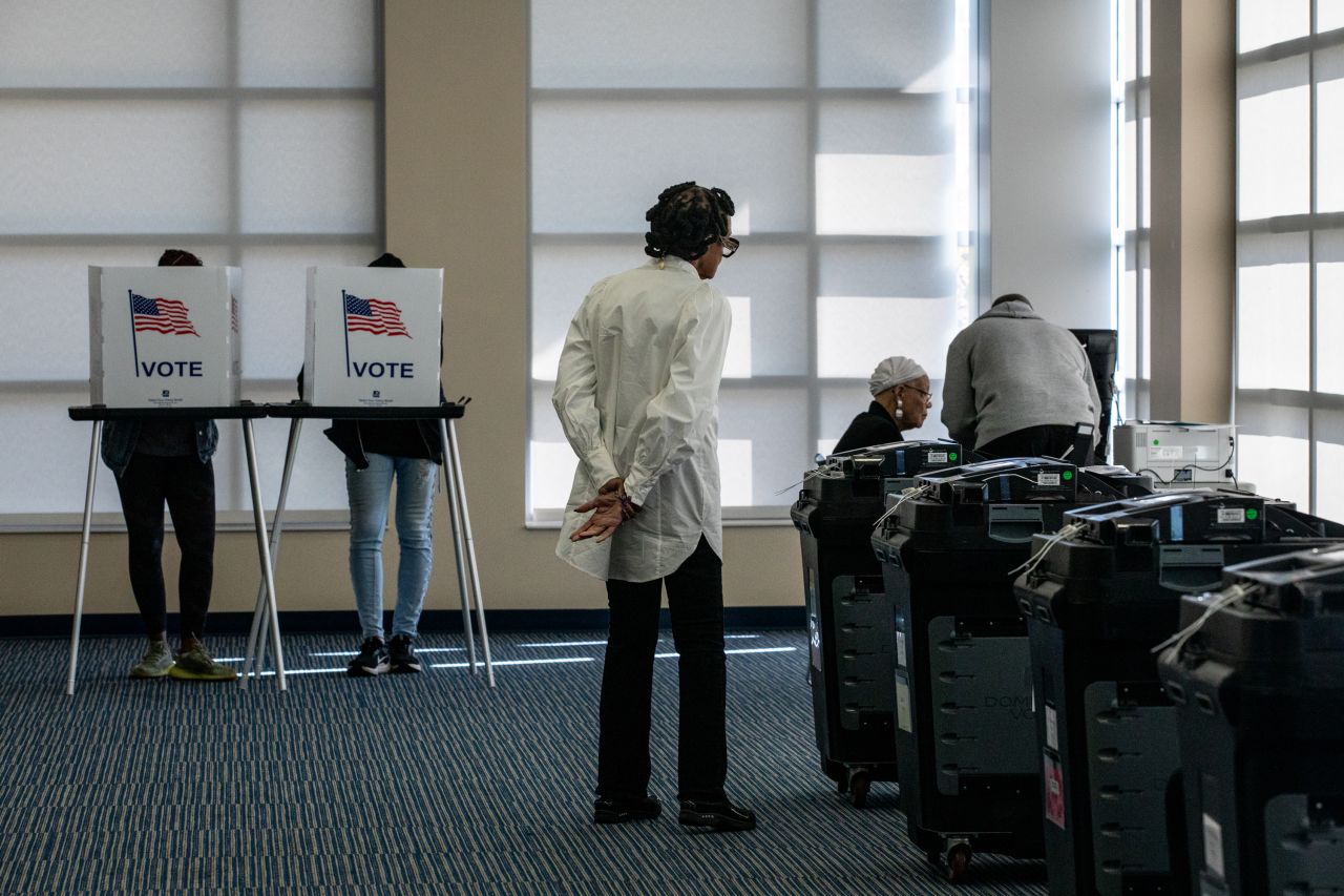 Election officials oversee tabulators as voters cast their ballots during the first day of early voting at a polling station in Detroit, Michigan, on October 19.