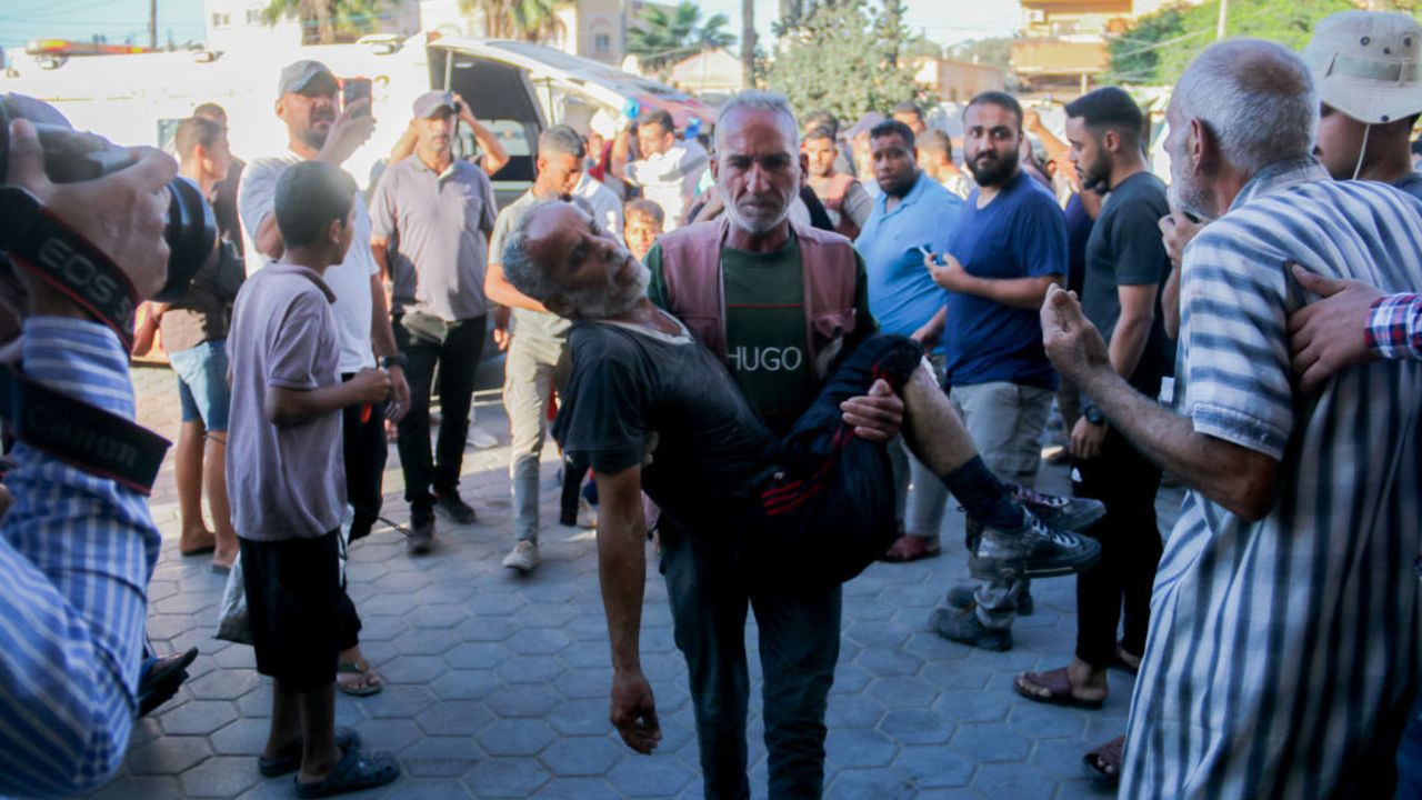 A Palestinian man carries an injured man following an Israeli airstrike  in western Deir al-Balah, central Gaza Strip, on October 20, 2024. (Photo by Saeed Jaras / Middle East Images / Middle East Images via AFP) (Photo by SAEED JARAS/Middle East Images/AFP via Getty Images)