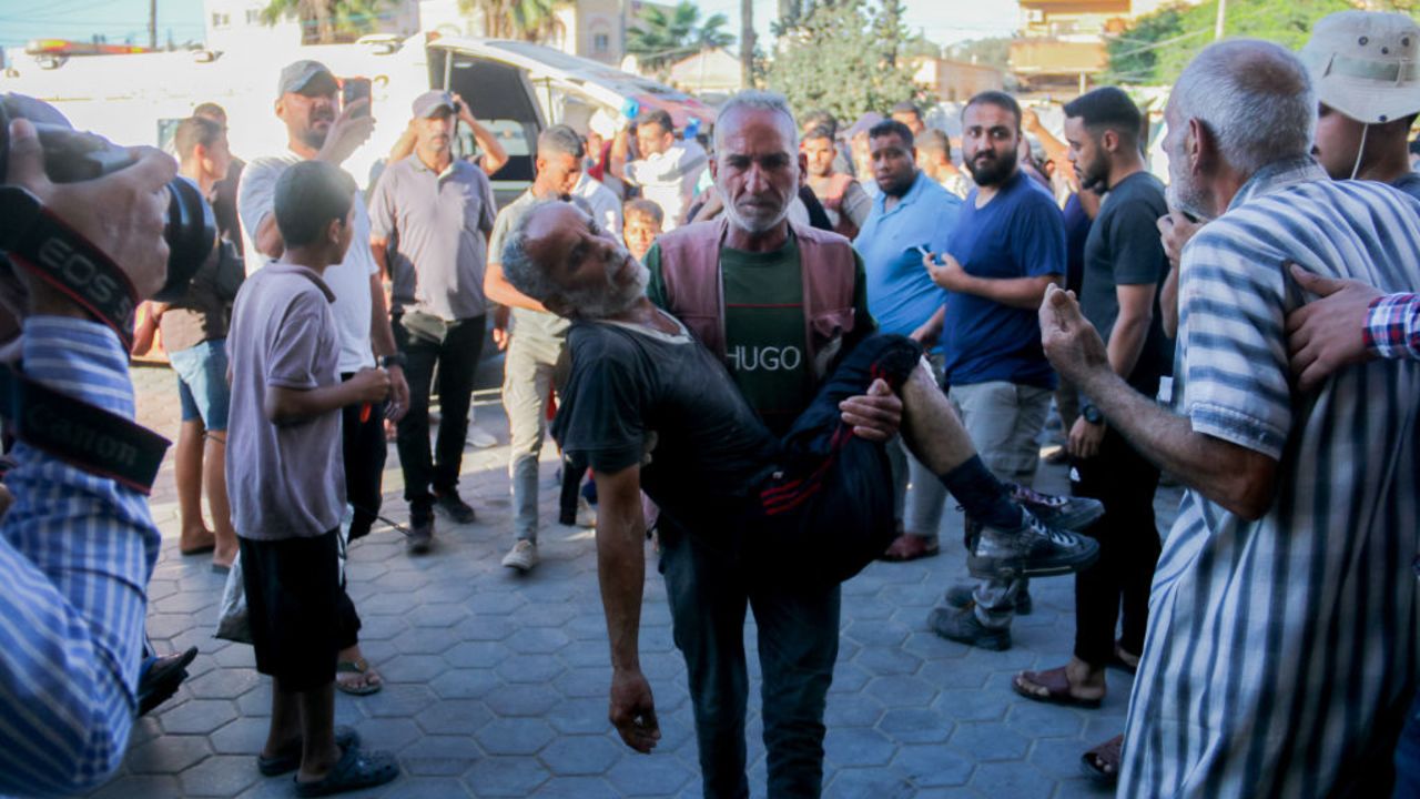A Palestinian man carries an injured man following an Israeli airstrike in western Deir al-Balah, central Gaza Strip, on October 20, 2024. (Photo by Saeed Jaras / Middle East Images / Middle East Images via AFP) (Photo by SAEED JARAS/Middle East Images/AFP via Getty Images)