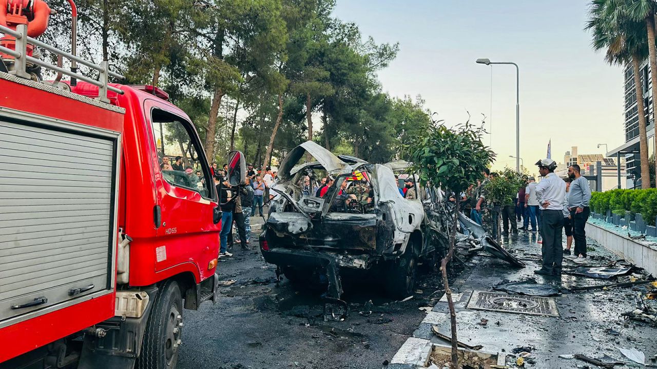 Syrian emergency and security services inspect the wreckage of a car that exploded in Damascus on Monday, October 21.